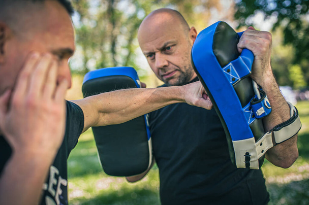Muay thai trainer holds focus mitts. Kick boxing training and demonstration with pads. Martial arts practice - Foto, afbeelding