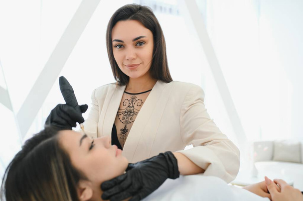 Cosmetologist applying permanent make up on eyebrows- eyebrow tattoo. - Valokuva, kuva