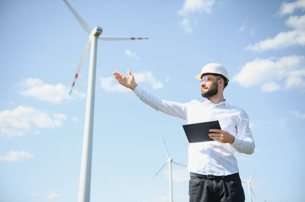 Male engineer working with plan inspecting or maintenance of wind turbines at windmill field farm - Φωτογραφία, εικόνα