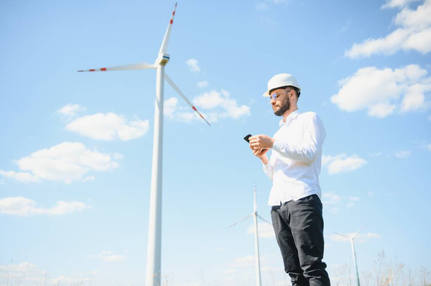 Engineer is checking energy production on wind turbine. Worker in windmills park. - Fotoğraf, Görsel