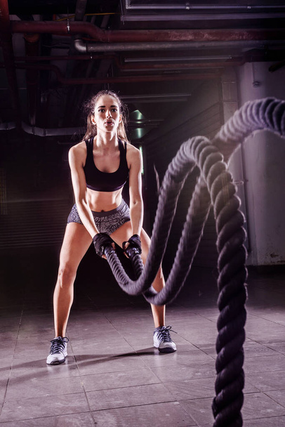 Battle ropes session. Attractive young fit and toned sportswoman working out in fitness training gym - Fotoğraf, Görsel
