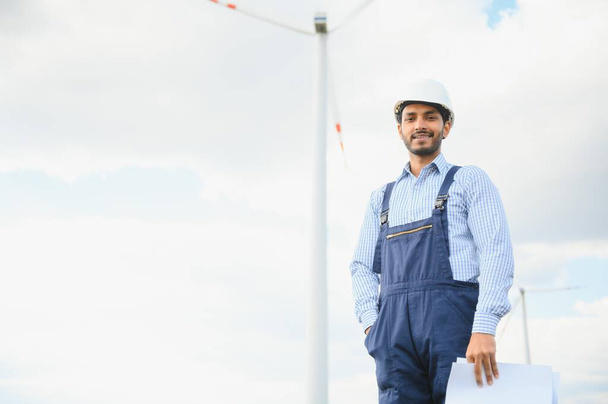 India engineer at windmill farm operation to generate electricity, Asian man working at wind turbine farm, Clean and green energy - Fotoğraf, Görsel