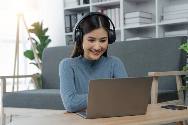 Mujer relajada escuchando música con auriculares en el portátil en casa. - Foto, imagen