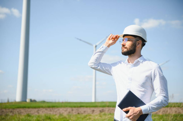 Engineer is checking energy production on wind turbine. Worker in windmills park. - Foto, afbeelding