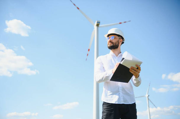 Engineer is checking energy production on wind turbine. Worker in windmills park. - Φωτογραφία, εικόνα