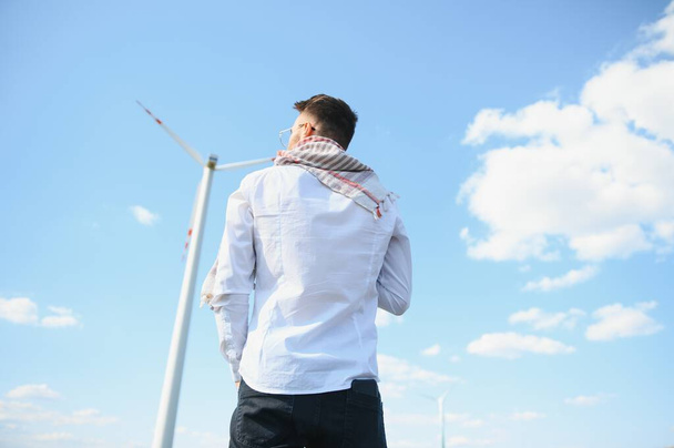 Arab man standing with wind turbine on mountain. - Zdjęcie, obraz
