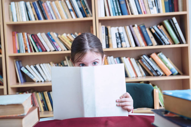 little girl reading book in library  - Foto, imagen