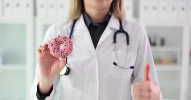 Dietista doctora sosteniendo rosquilla y señal de ok. Recomendación y comentarios Pulgares hacia arriba y beneficios de los dulces - Metraje, vídeo