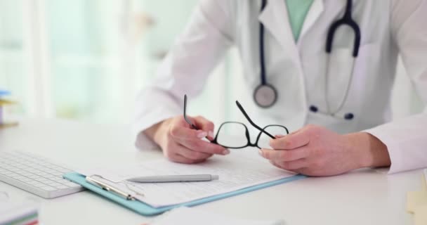 Les mains féminines du médecin tiennent les lunettes sur le lieu de travail dans la lame. Services médicaux et assurances - Séquence, vidéo