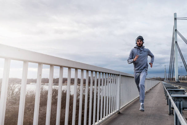 Мужчина городской бегун, занимающийся интенсивной тренировкой на открытом воздухе утром - Фото, изображение