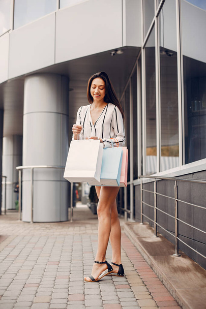 Beautiful girl in a summer city. Lady with shopping bags - Foto, imagen