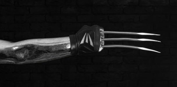hand with blade claw weapon on black background - 写真・画像