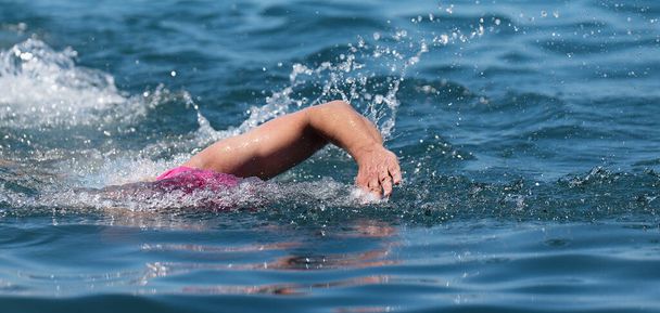 Professional triathlete man swimming crawl in the ocean, freestyle crawl in ocean. Swimming man in clean ocean water. Open water swimming - Foto, imagen