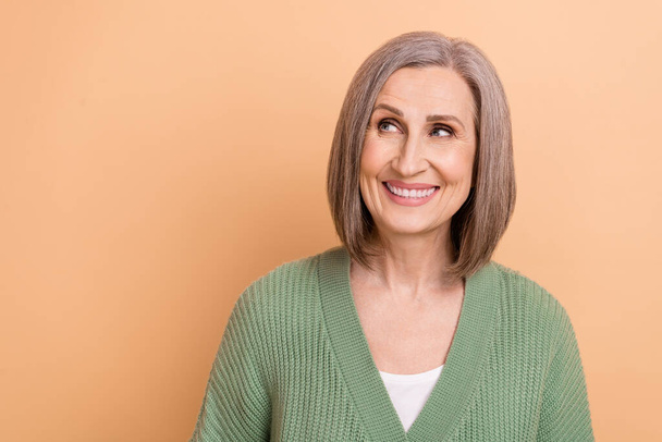 Portrait of senior attractive lady khaki cardigan smiling grey hair looking empty space shopping offer isolated on beige color background. - Fotografie, Obrázek