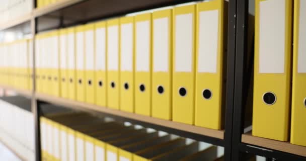 Yellow identical folders with materials and documents are arranged in rows on shelves. Storage of business documents - Footage, Video