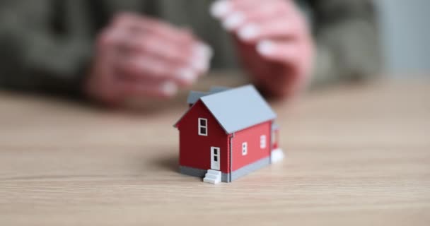Agent nieruchomości chroni model czerwonego domu zbliżenie. Zakup i ubezpieczenie domu i wynajem - Materiał filmowy, wideo