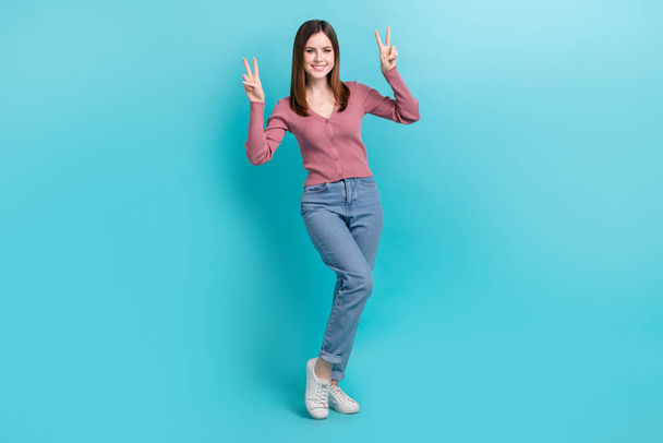 Full length foto di felice donna sorridente indossare camicia rosa jeans denim shopping show dita doppio v-segno isolato su sfondo di colore ciano. - Foto, immagini