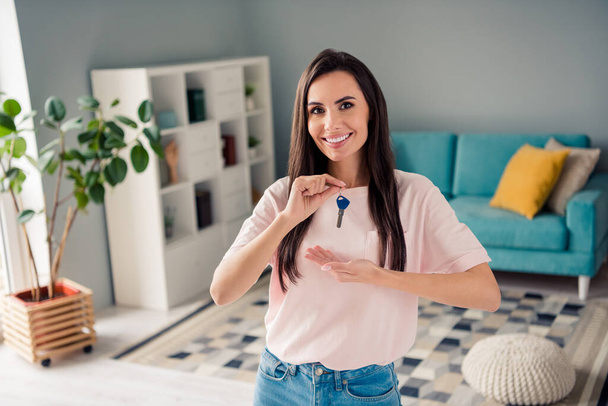 Photo of good mood pretty young girl wear pink t-shirt smiling showing arms hands news apartment keys indoors home room. - Фото, зображення