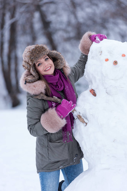 fiatal nő hóemberrel a téli parkban - Fotó, kép
