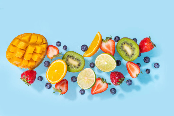 Summer vitamin food concept, various fruit and berries mango peach mint plum apricots blueberry currant, creative flat lay on light blue background top view copy space - Photo, Image