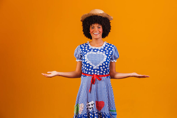 Brazilian afro woman wearing typical clothes for the Festa Junina in yellow background - Фото, зображення