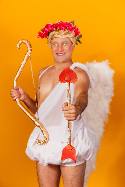 Valentine's day concept. Portrait of the God of love - Cupid with bow and arrow on a yellow background. - Photo, image