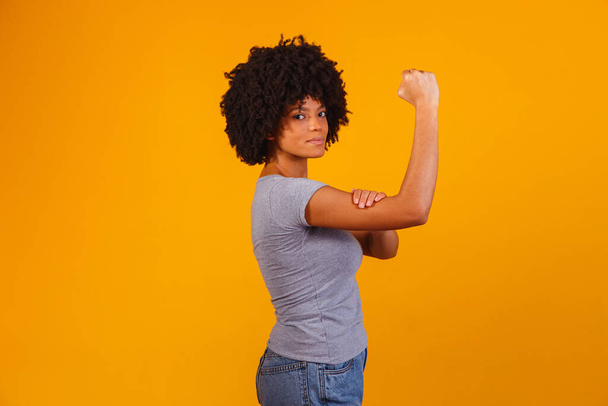 We can do it. Woman's fist of female power. Woman victim of racism. Abuse at work. The feminine power. Female empowerment. The strength of women. Yellow background. - Foto, Imagem