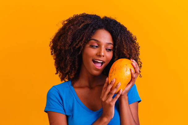 Young beautiful woman holding papaya over yellow isolated background - Foto, afbeelding