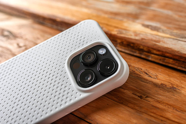 Camera of a modern smartphone close-up on a wooden background. - Foto, immagini