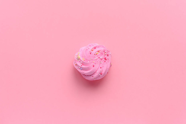 Stilleven van een zeer kleurrijke meringues, met gekleurde hagelslag op, geplaatst op een roze achtergrond. Een enkele meringue ligt in het midden van het frame. Veel kopieerruimte rondom. - Foto, afbeelding