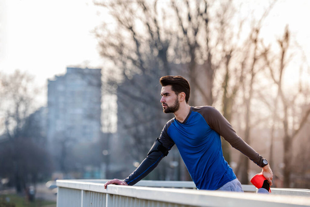 Urban Man Jogger Stretching Leg Outdoors Before Running  - Photo, image