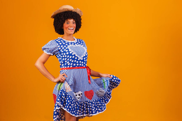 Brazilian afro woman wearing typical clothes for the Festa Junina in yellow background - Valokuva, kuva