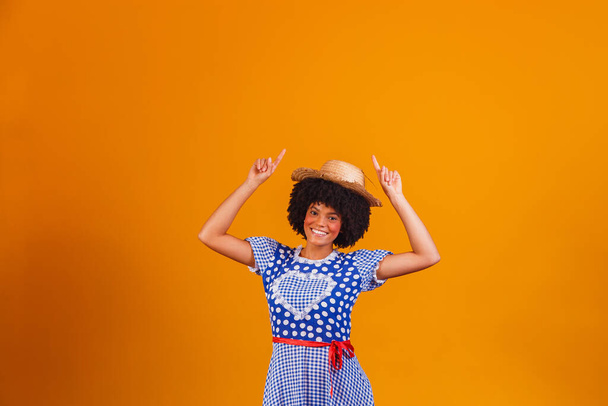 Brazilian afro woman wearing typical clothes for the Festa Junina in yellow background - Zdjęcie, obraz