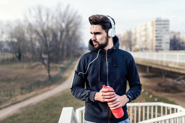 Urban handsome man runner with earphones taking brake - Fotografie, Obrázek