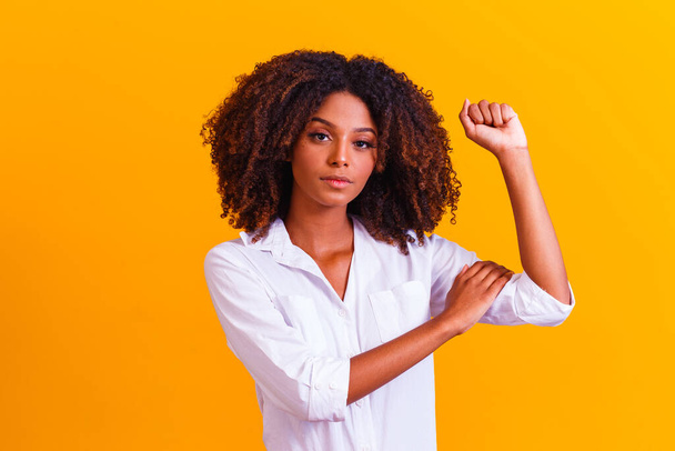 We can do it. Woman's fist of female power. Woman victim of racism. Abuse at work. The feminine power. Female empowerment. The strength of women. Yellow background. - Foto, immagini