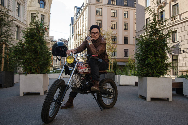 Shot van trendy hipster rijden ouderwetse vintage motorfiets buiten. - Foto, afbeelding