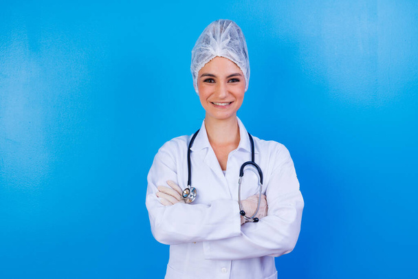 Portrait of confident with toothy beaming smile qualified experienced clever intelligent doctor wearing white formal wear she is standing with crossed folded arms, isolated on blue background - Fotografie, Obrázek