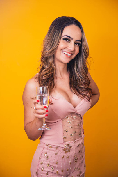 beautiful caucasian woman on yellow background holding a glass of champagne, celebrating. - Photo, Image