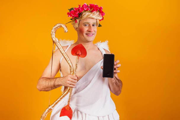 cupid holding cell phone. Valentine's Day promotion - Φωτογραφία, εικόνα