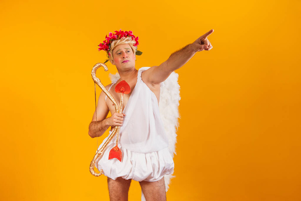 Valentine's day concept. Portrait of the God of love - Cupid with bow and arrow on a yellow background. - Foto, Imagem