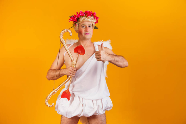 Valentine's day concept. Portrait of the God of love - Cupid with bow and arrow on a yellow background. - Photo, image