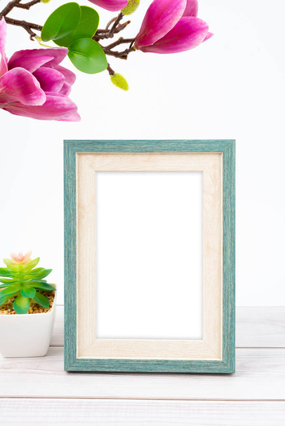 Blank picture frame with magnolia flower on white floor with copy space and clipping path for the inside. - Foto, Imagem