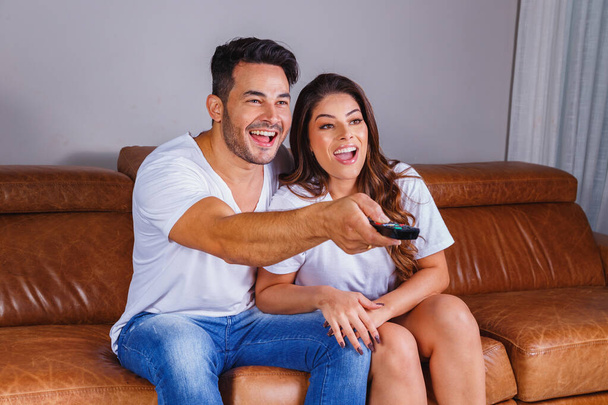 valentine couple with remote control watching television on the comfortable sofa - Photo, image