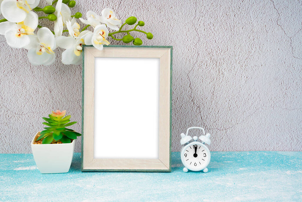 Blank picture frame and alarm clock on blue floor with copy space and clipping path for the inside. - Valokuva, kuva
