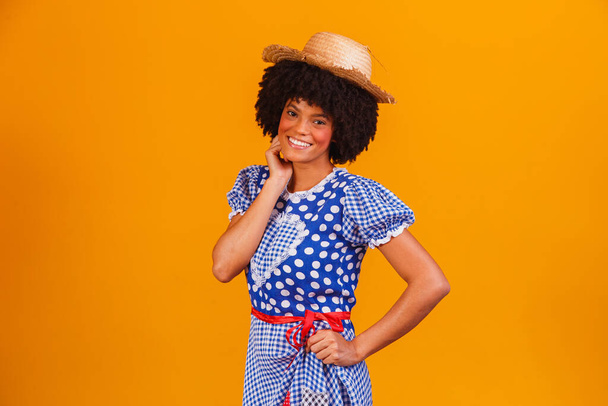 Brazilian afro woman wearing typical clothes for the Festa Junina in yellow background - Fotó, kép