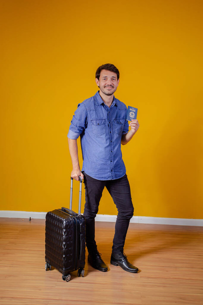 man with suitcase and passport on yellow background. travel concept - 写真・画像