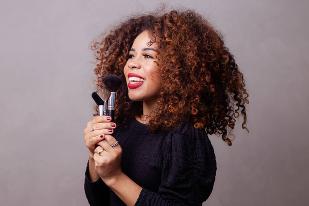 Afro woman professional makeup artist holding makeup brushes. - Foto, Imagen
