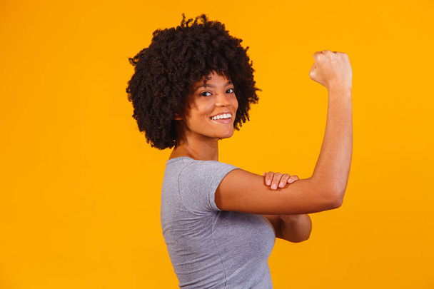 We can do it. Woman's fist of female power. Woman victim of racism. Abuse at work. The feminine power. Female empowerment. The strength of women. Yellow background. - Foto, Bild