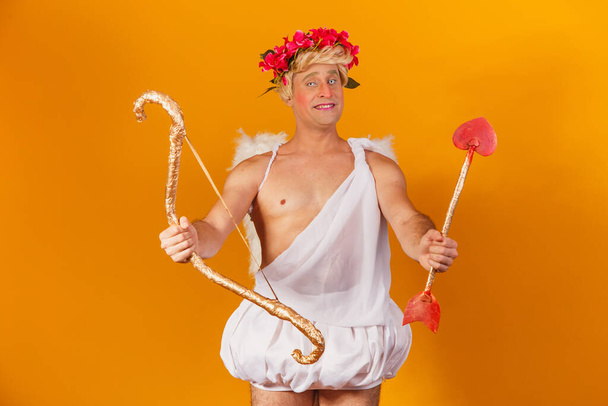 Valentine's day concept. Portrait of the God of love - Cupid with bow and arrow on a yellow background. - Fotoğraf, Görsel