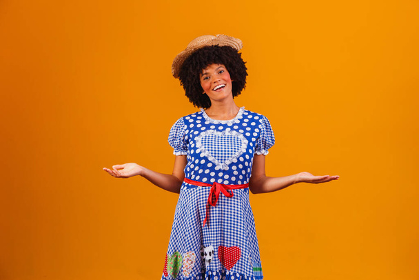 Brazilian afro woman wearing typical clothes for the Festa Junina in yellow background - Foto, imagen